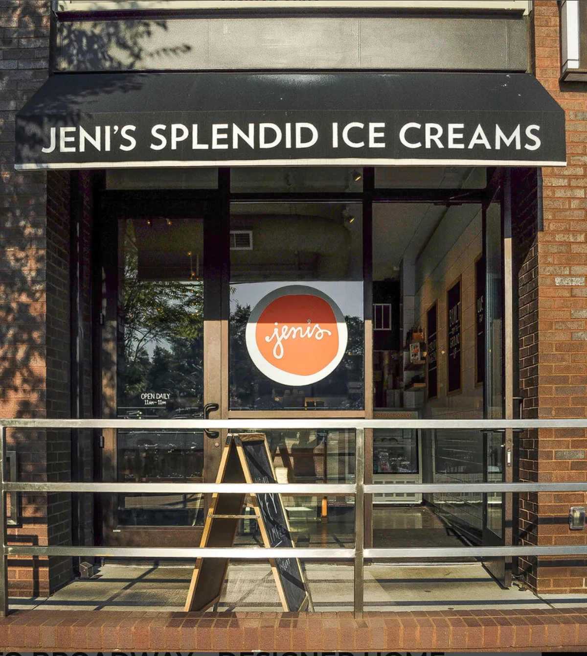 A cheerful exterior view of Jeni’s Splendid Ice Creams, showcasing the storefront sign, menu board, and inviting glass doors. The scene is lively, evoking the joy of savoring gourmet ice cream and socializing on a bright day.