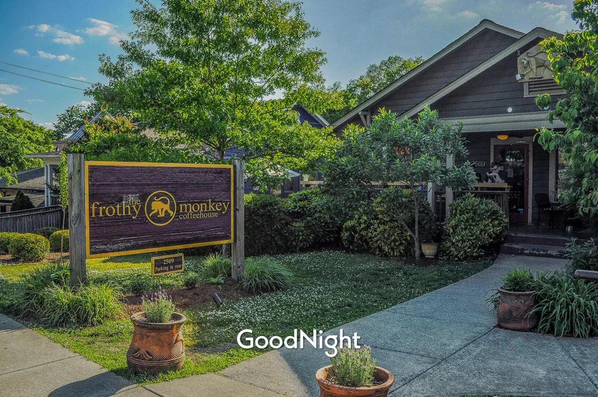 A welcoming exterior image of Frothy Monkey, highlighting the coffeehouse’s sign, entrance, and lush greenery. The scene suggests a perfect spot for morning coffee or catching up with friends in a relaxed, neighborhood atmosphere.