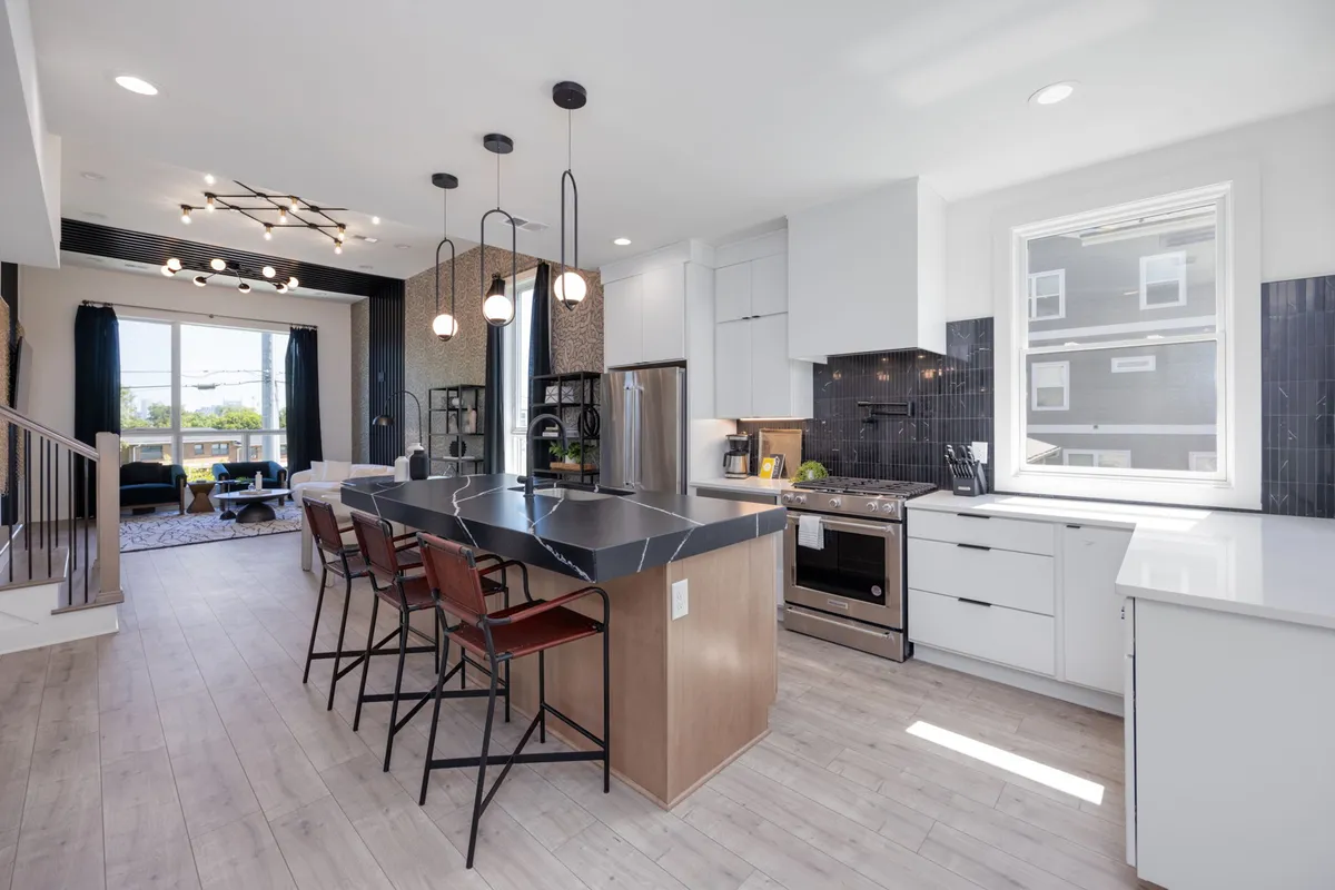 A spacious, modern kitchen with a large central island, stainless steel appliances, and a generous window letting in natural light. The island allows for prepping, casual dining, or social gatherings. The overall vibe is welcoming, perfect for cooking and entertaining.