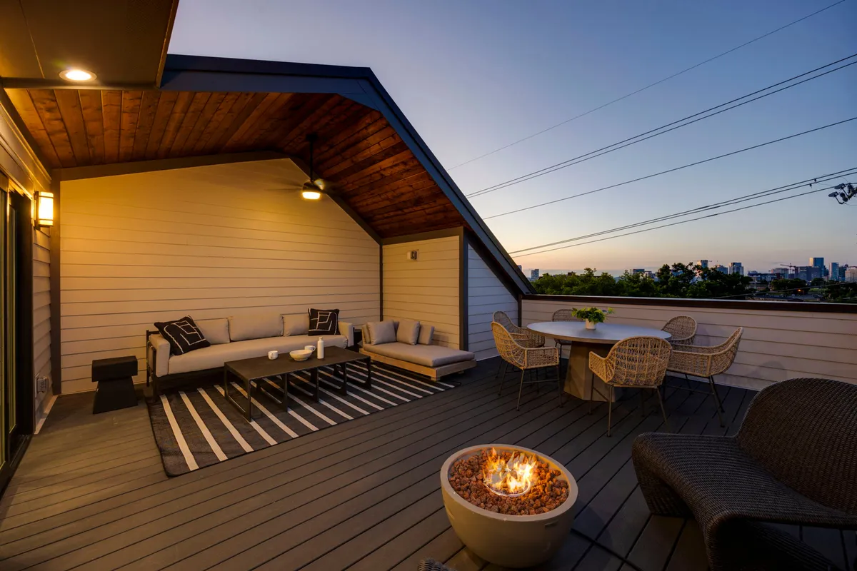 An inviting exterior fire pit and seating area, paired with a dining table and the city skyline beyond. The space is ideal for evening conversations, outdoor meals, and enjoying the city lights after a busy day.