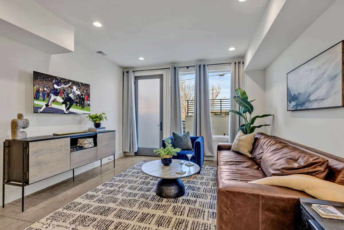 A cozy and inviting living room featuring a leather sofa, blue accent chair, coffee table, wall art, and a television. The area is arranged to foster conversation and group activities, with comfortable seating and a welcoming ambiance.